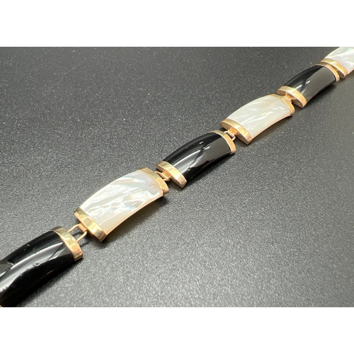1001 - A 9ct gold 8 panel onyx and mother of pearl bracelet with push clasp and safety clip. Chinese charac... 