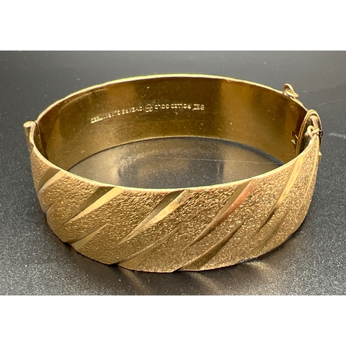 1033 - A vintage 9ct rolled gold bangle with brushed effect and diamond cut pattern. Marks to inside of ban... 