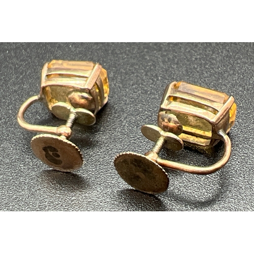 1005 - A pair of yellow metal screw back earrings each set with an emerald cut citrine stone. Unmarked but ... 