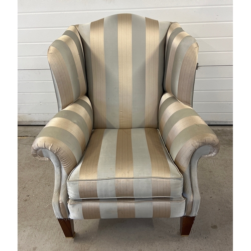 1404 - A modern Duresta wing back arm chair with brass caster front feet and gold striped upholstery.