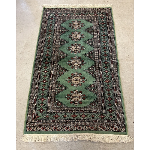 1406 - A vintage green ground rug with fringed ends, approx. 176cm x 93cm.