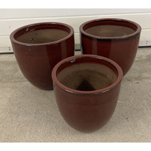 1372 - 3 modern dark red glazed garden pots. A pair of large pots together with a smaller pot. Largest appr... 