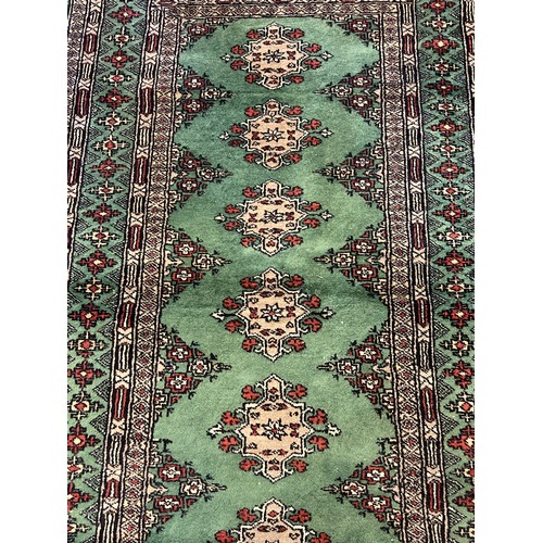 1406 - A vintage green ground rug with fringed ends, approx. 176cm x 93cm.