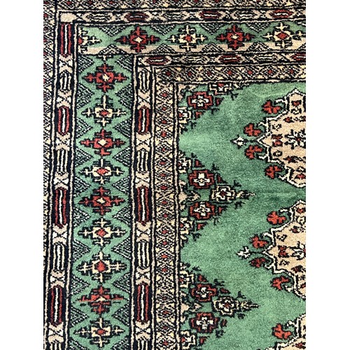 1406 - A vintage green ground rug with fringed ends, approx. 176cm x 93cm.