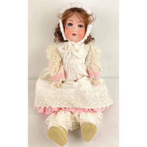 An antique 22" Armand Marseille 390 doll with bisque head and jointed composite body. Closing blue eyes, brown hair and hand painted face. Dressed in handmade and vintage clothing. Marked to back of head Armand Marseille Germany 390 A 5 M.