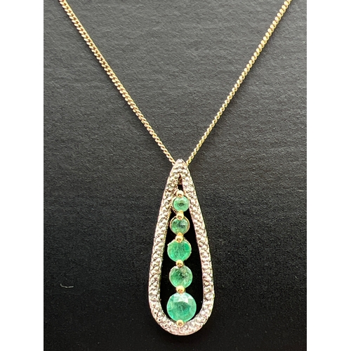 1014 - A teardrop shaped emerald and diamond pendant with 5 graduating emeralds haloed with 4 illusion set ... 