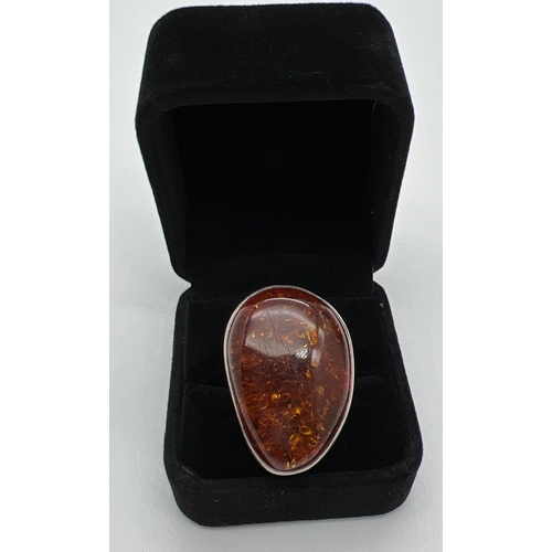 1016 - A very large cognac amber set silver dress ring. Stamped 925 to underside. Ring size P½. Amber appro... 