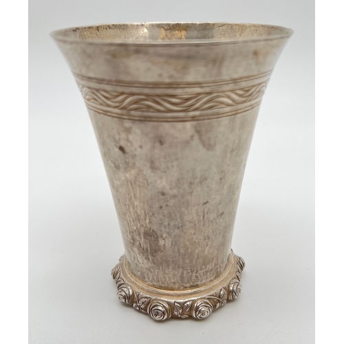 1223 - An Omar Ramsden Arts & Crafts silver beaker of hammered conical form with rose design rim to base. F... 