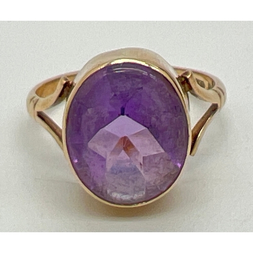 1048 - A 9ct gold and amethyst set dress ring. A large oval cut bezel set amethyst with shaped shoulders to... 