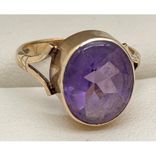 1048 - A 9ct gold and amethyst set dress ring. A large oval cut bezel set amethyst with shaped shoulders to... 