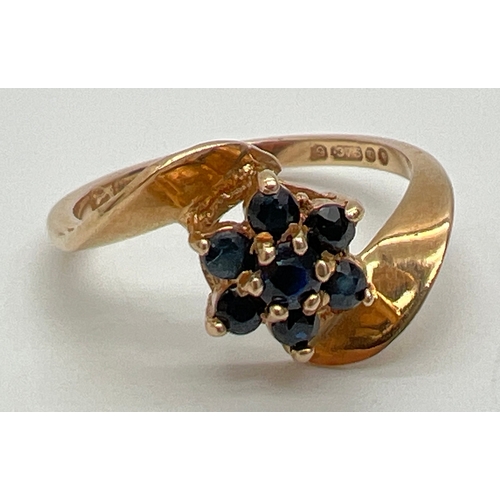 1056 - A 9ct gold flower design sapphire set dress ring in a twist design mount. Central small round cut sa... 