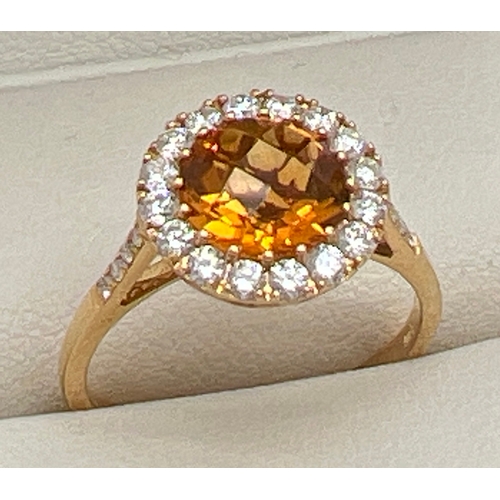 An 18ct gold, citrine and diamond cluster style ring by Luke Stockley, London. Central rose cut 2ct citrine stone with a halo of small round cut diamonds, and diamond set shoulders. Diamonds total approx. 0.48ct. Full hallmarks to inside of band with makers name. Ring size O, total weight approx. 2.8g.