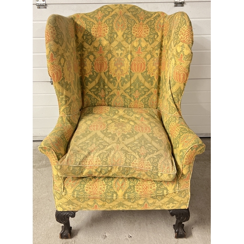 1414 - An antique dark wood wing back chair with ball and claw carved front feet and green, yellow and oran... 