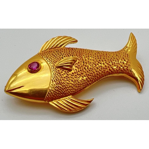 A 22ct gold brooch in the shape of a fish set with oval cut ruby eye. Patterned detail to body with ridged decoration to fins. Back stamped 916, brooch size 3cm x 5.5cm. Total weight approx. 15.9g.