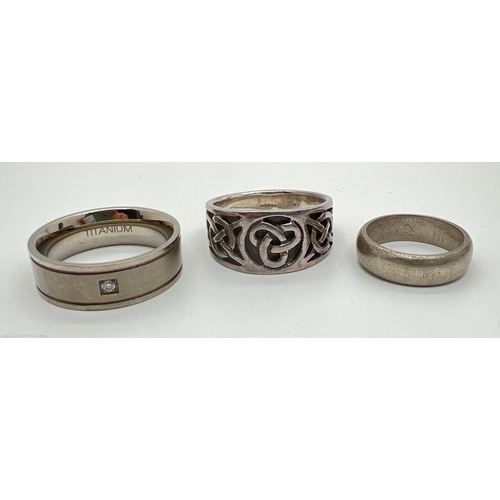 31 - 3 band rings. A large silver celtic knot design ring, a titanium band ring set with a small clear st... 