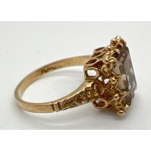 42 - A vintage 9ct gold, claw set smoked quartz dress ring. Central emerald cut smoked quartz in decorati... 