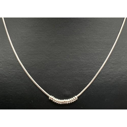 55 - A modern design 18 inch silver snake chain necklace with moving small circular bead decoration. Silv... 