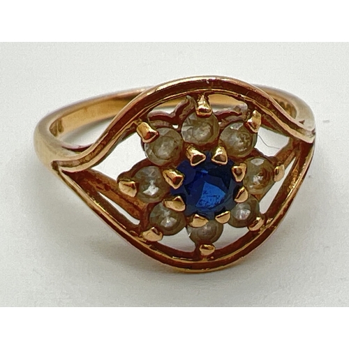 A vintage 9ct gold sapphire and clear stone cluster style ring in halo style mount. Central round cut sapphire surrounded by 8 clear stones. Full hallmarks to inside of band, size N. Total weight approx. 2.6g.