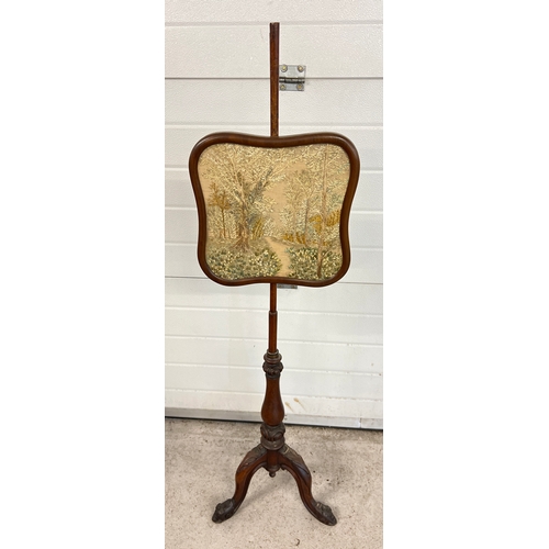 1329 - A Victorian mahogany pole screen with needlepoint panel depicting a wooded scene with flowers. Raise... 