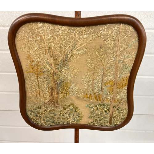 1329 - A Victorian mahogany pole screen with needlepoint panel depicting a wooded scene with flowers. Raise... 