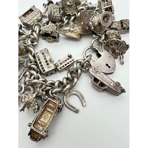 1016 - A vintage silver charm bracelet with large padlock clasp and 29 silver and white charms - some openi... 