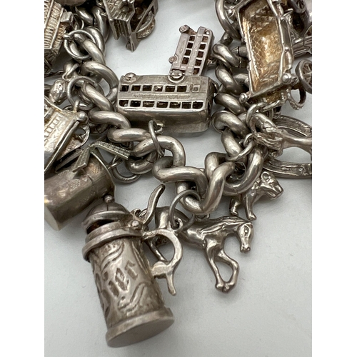 1016 - A vintage silver charm bracelet with large padlock clasp and 29 silver and white charms - some openi... 