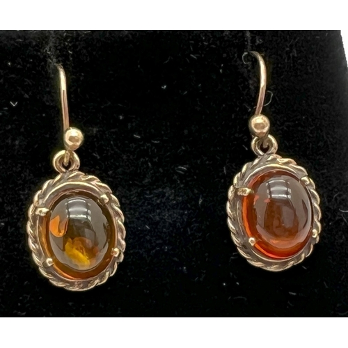 1022 - A pair of unmarked gold drop earrings set with cabochons of amber with rope detail to mounts. Test a... 