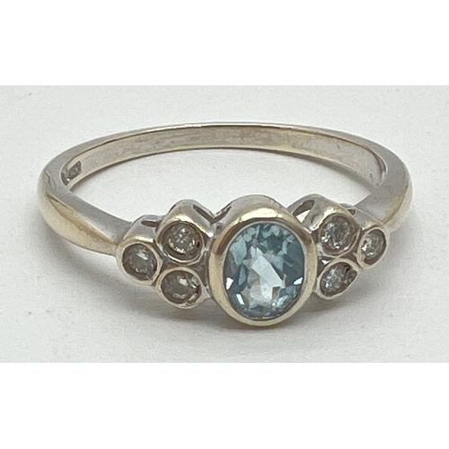 1004 - A 9ct white gold bezel set aquamarine and diamond dress ring. Central oval cut aquamarine with 3 sma... 