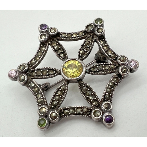 1027 - A vintage silver brooch modelled as a star/spiders web, set with round cut coloured stones and marca... 