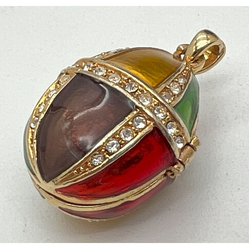 1035 - A yellow metal harlequin enamelled pendant, modelled as an egg, with clear stone set detail. With hi... 