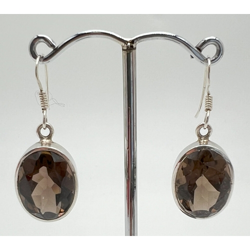 1037 - A pair of 925 silver drop earrings set with large oval faceted smoked quartz stones. Hooked posts st... 
