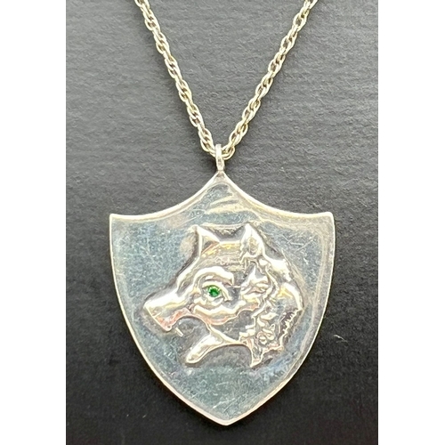 1044 - A modern silver shield shaped pendant necklace designed with a wolfs head and set with a small green... 