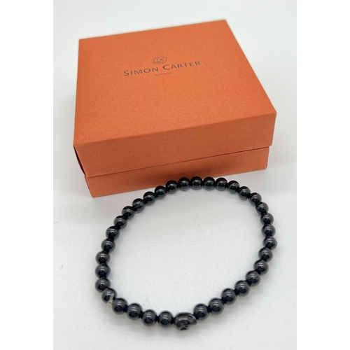 1053 - A new in box black onyx circular and skull bead expanding bracelet by Simon Carter, London.