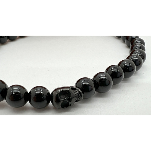 1053 - A new in box black onyx circular and skull bead expanding bracelet by Simon Carter, London.