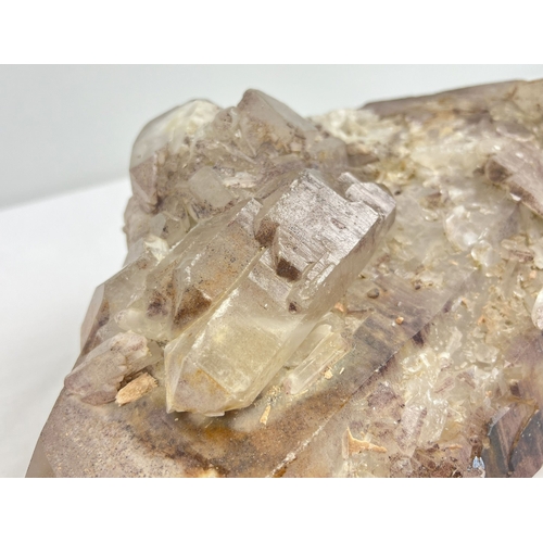 1309 - A large 7.8 kg double terminated smoked quartz crystal point with hematite inclusions and multiple c... 