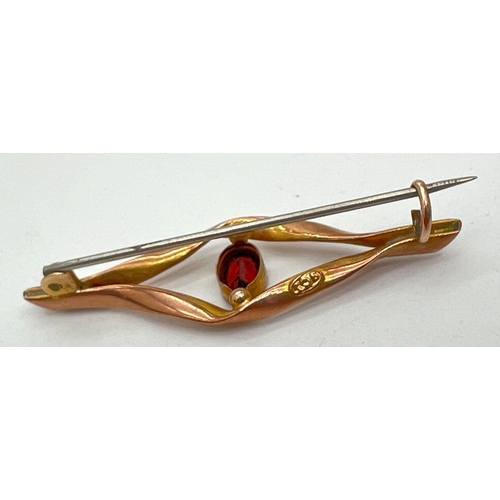 1002 - A 9ct gold brooch of twist design set with central oval cut garnet stone. Marked '9ct' to reverse. A... 