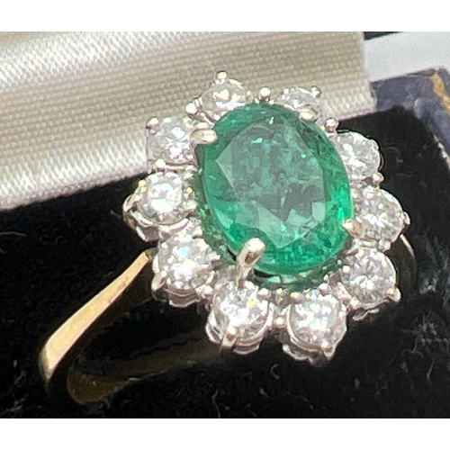 1157 - An 18ct gold, emerald and diamond cluster ring. A central oval cut emerald surrounded by 10 round cu... 