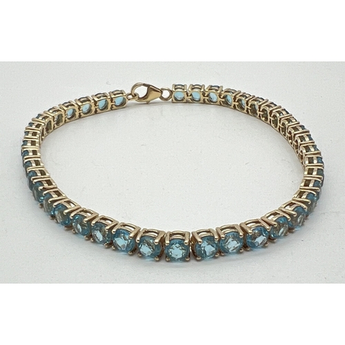 1013 - A silver gilt tennis bracelet set with 41 round cut blue topaz stones. Silver marks to lobster style... 