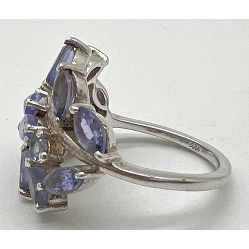 1014 - A silver floral design Tanzanite set dress ring. Top of ring set with 12 marquise cut and 2 round cu... 