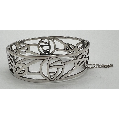 1029 - A boxed silver pierced work Rennie Mackintosh rose design bangle with slide clasp and safety chain. ... 