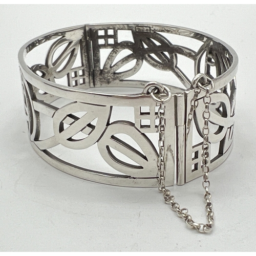 1029 - A boxed silver pierced work Rennie Mackintosh rose design bangle with slide clasp and safety chain. ... 