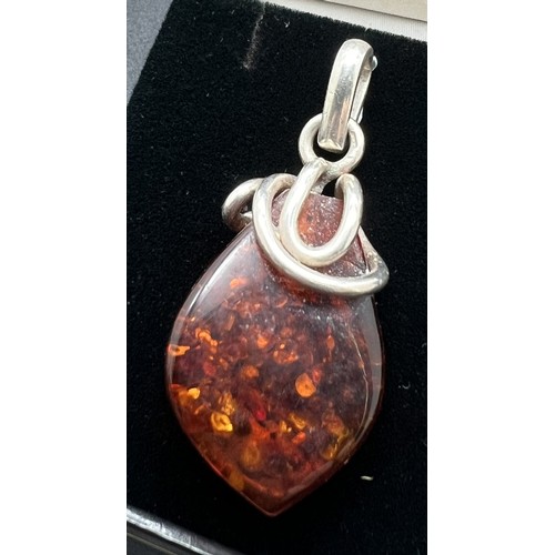 1033 - 2 items of amber set silver jewellery. A teardrop shaped cognac amber pendant with scribble design c... 