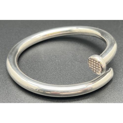 1034 - A large modern design silver bangle modelled as a nail with  diamond pattern to nail head. Silver ma... 