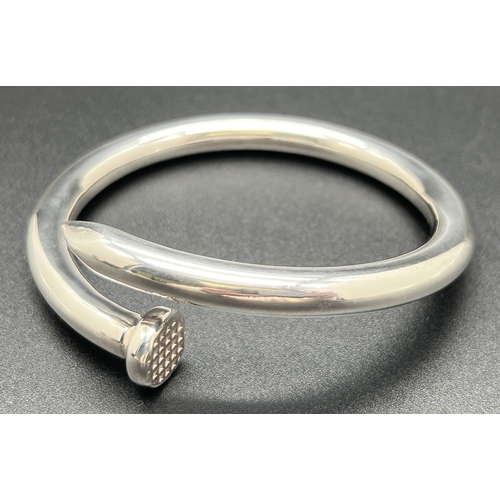 1034 - A large modern design silver bangle modelled as a nail with  diamond pattern to nail head. Silver ma... 
