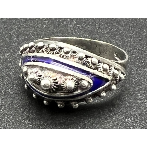 1035 - A silver ethnic design cathedral style dress ring with blue enamel detail. Central bead decoration s... 