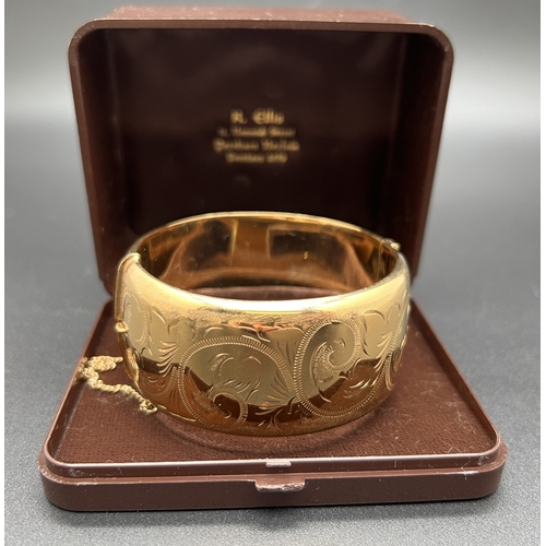 1041 - An vintage Excalibur rolled gold wide bangle with half engraved decoration of scroll & foliate desig... 