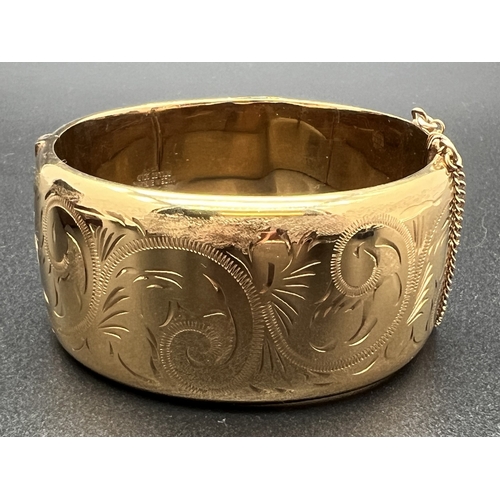 1041 - An vintage Excalibur rolled gold wide bangle with half engraved decoration of scroll & foliate desig... 