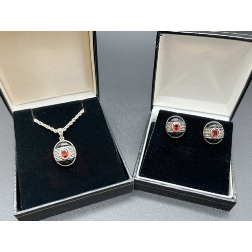 1005 - A silver pendant necklace and matching stud earrings each set with black onyx, garnets and marcasite... 