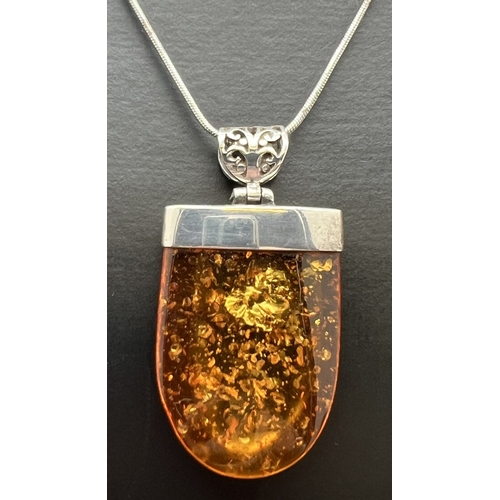 1043 - A modern design large amber pendant with silver cap and pierced work bale. Silver mark to top of cap... 