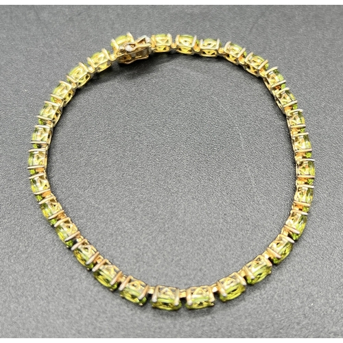 1050 - A modern design silver gilt bracelet set with 30 oval cut peridot stones. Push clasp with double saf... 